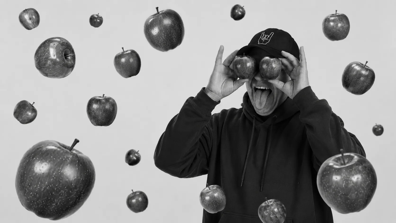 Person in a hoodie holding apples over their eyes, apples floating around